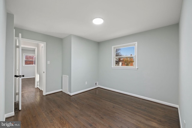 unfurnished bedroom featuring dark wood-style flooring, multiple windows, and baseboards