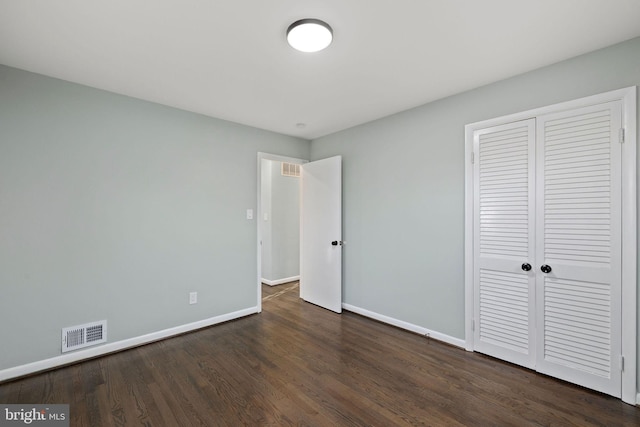 unfurnished bedroom featuring a closet, wood finished floors, visible vents, and baseboards