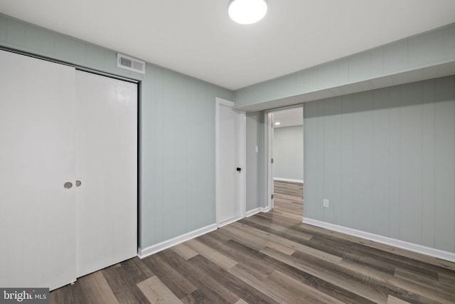 unfurnished bedroom with a closet, wood finished floors, visible vents, and baseboards