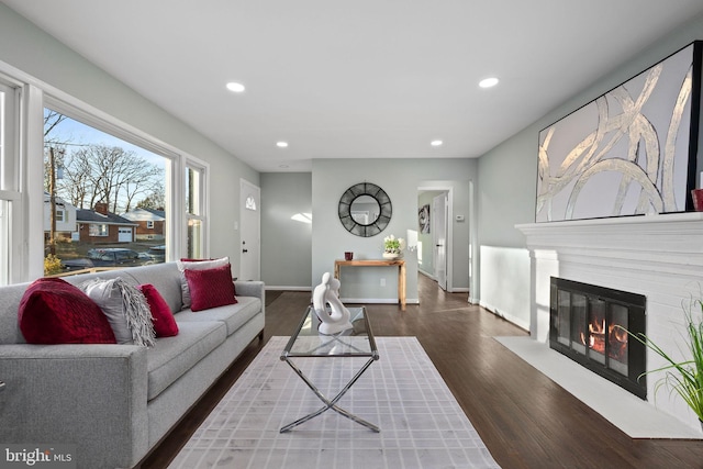 living area featuring a fireplace with flush hearth, recessed lighting, baseboards, and wood finished floors