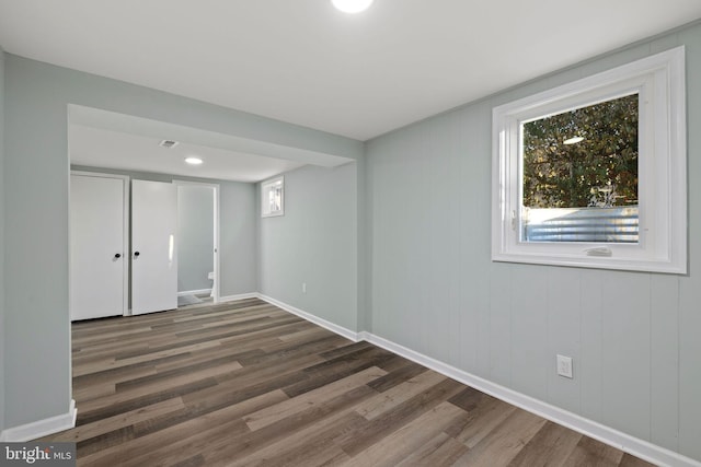 unfurnished room featuring wood finished floors, a wealth of natural light, and baseboards