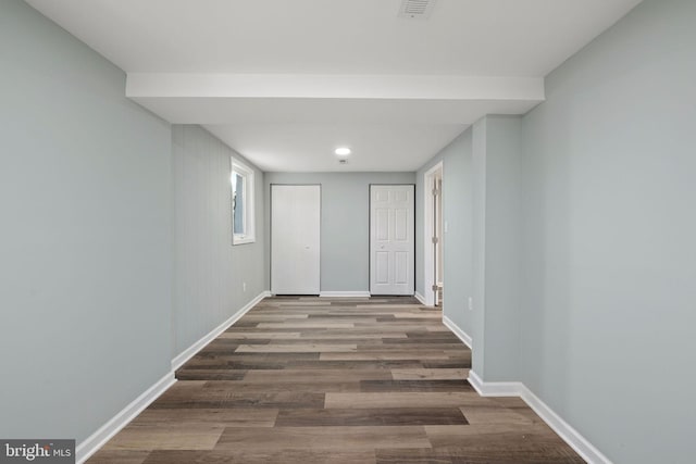 hallway featuring visible vents, baseboards, and wood finished floors