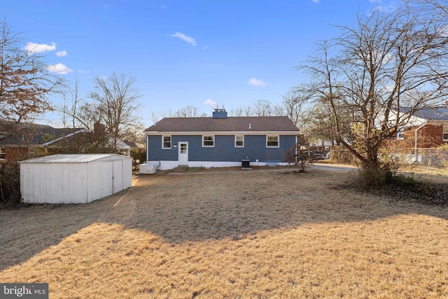 back of property featuring a shed, a lawn, and an outdoor structure