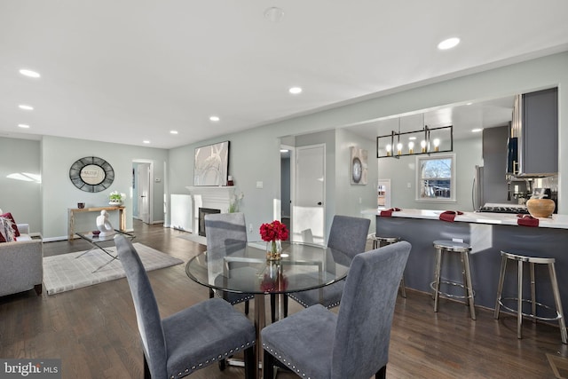 dining room featuring baseboards, dark wood-type flooring, a fireplace, and recessed lighting