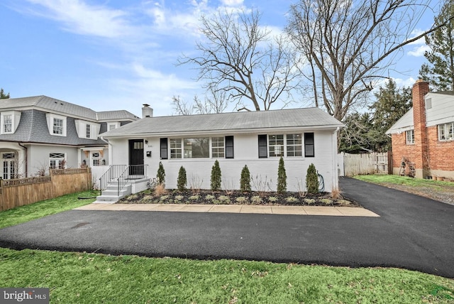 view of front of home featuring brick siding, driveway, and fence