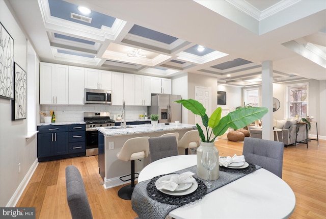 dining space with light wood-style floors, coffered ceiling, and baseboards