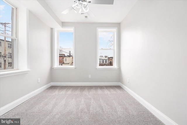 carpeted spare room with a ceiling fan, visible vents, and baseboards