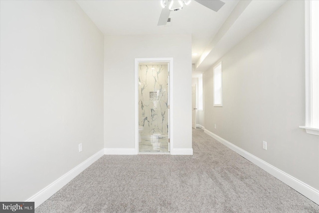 spare room featuring carpet, baseboards, and ceiling fan