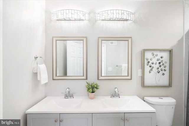 full bathroom with double vanity, toilet, and a sink