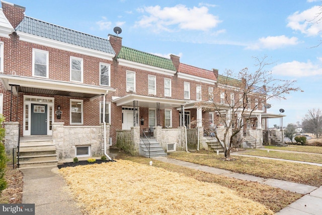 view of property featuring a porch, a tile roof, and brick siding