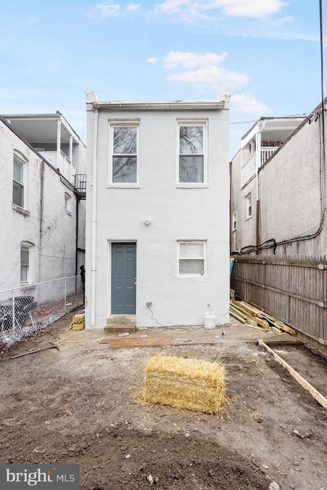 rear view of property featuring fence and stucco siding