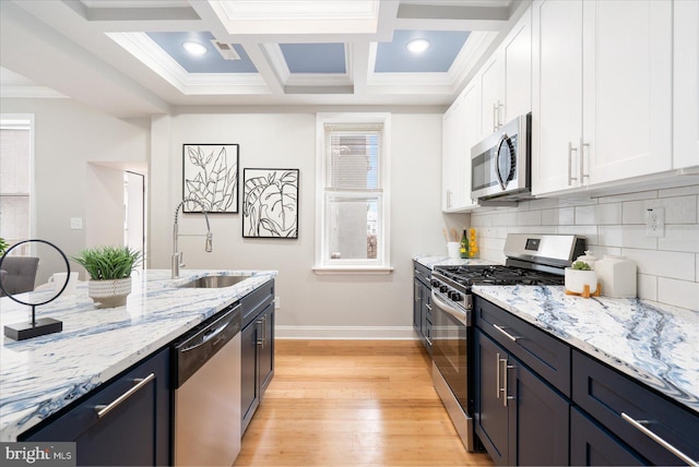 kitchen featuring white cabinets, backsplash, stainless steel appliances, and a sink