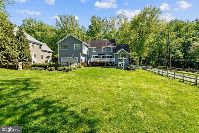 rear view of house featuring a garage, fence, and a lawn