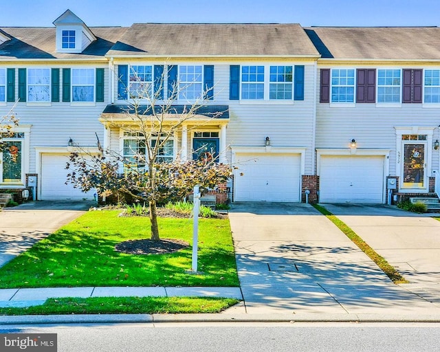 townhome / multi-family property with an attached garage, driveway, brick siding, and a front yard