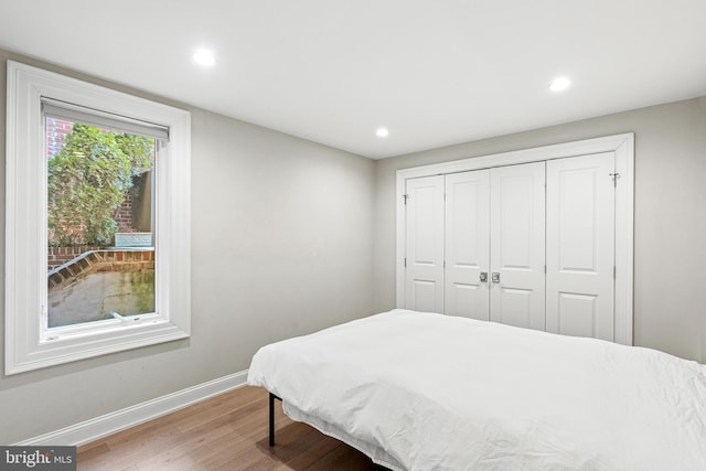 bedroom featuring a closet, recessed lighting, wood finished floors, and baseboards