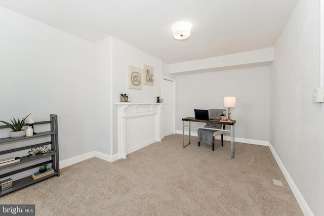 office area featuring light carpet and baseboards