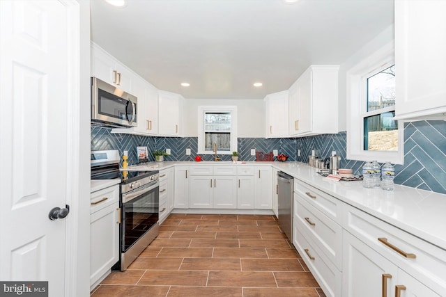 kitchen featuring appliances with stainless steel finishes, light countertops, a sink, and white cabinetry