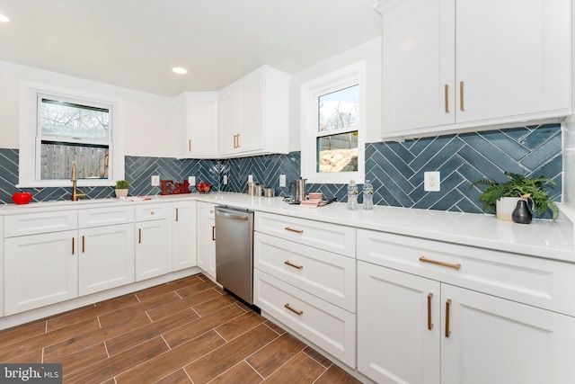 kitchen with light countertops, stainless steel dishwasher, wood tiled floor, and white cabinets