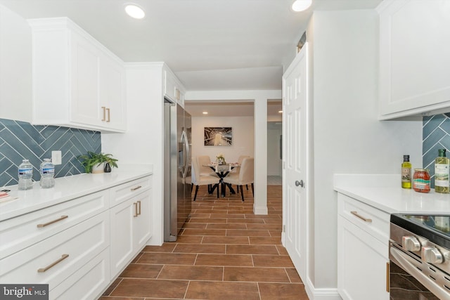 kitchen featuring white cabinets, stainless steel appliances, wood tiled floor, and light countertops