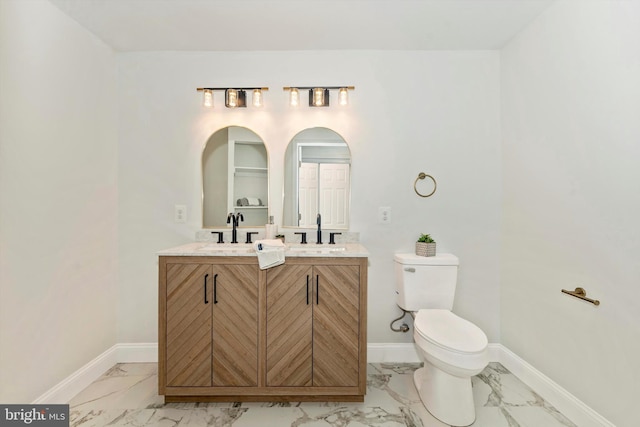 bathroom featuring marble finish floor, a sink, baseboards, and double vanity