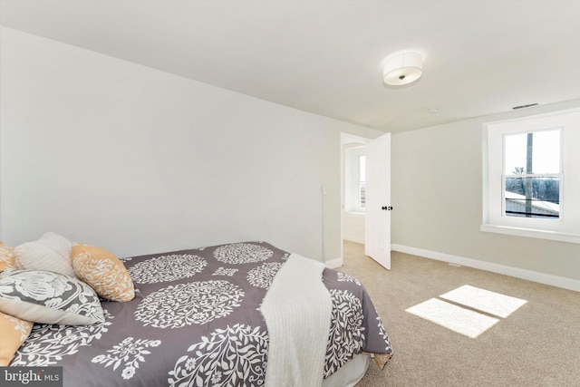 bedroom with baseboards, visible vents, and light colored carpet