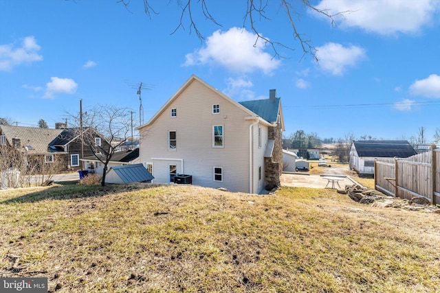 view of side of home featuring a yard, central AC, fence, and a chimney