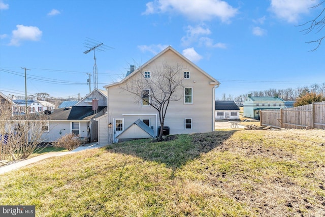 back of house featuring a lawn and fence