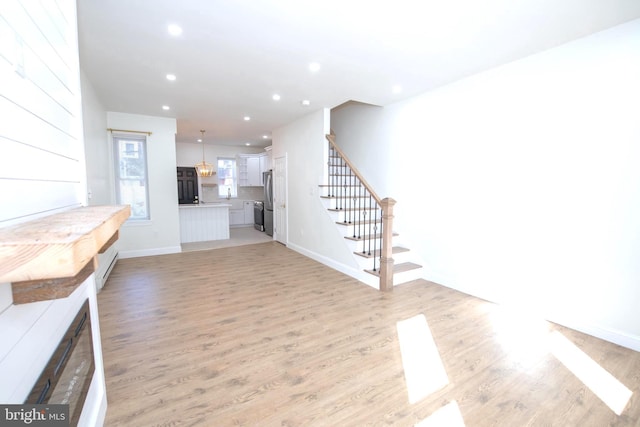 unfurnished living room with stairs, light wood finished floors, baseboards, and recessed lighting