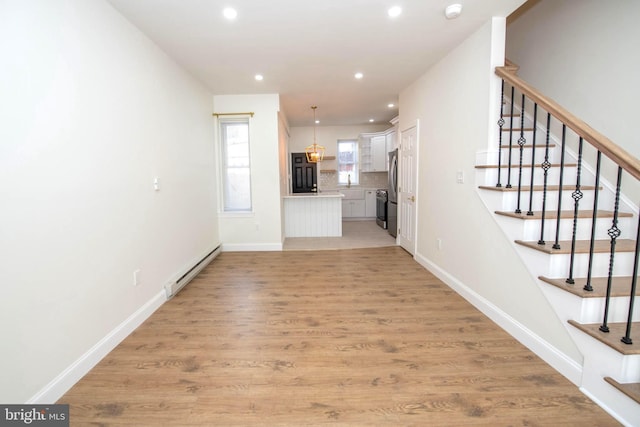 unfurnished living room with light wood-style floors, baseboards, and baseboard heating