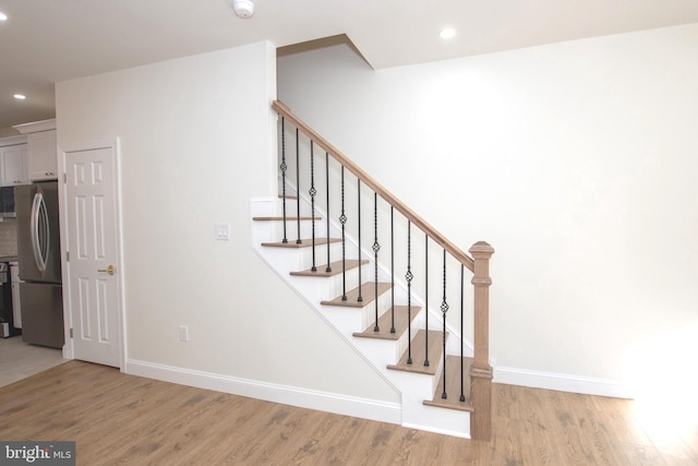 stairway featuring baseboards, wood finished floors, and recessed lighting