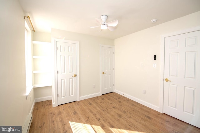 unfurnished bedroom with light wood finished floors, baseboard heating, and baseboards