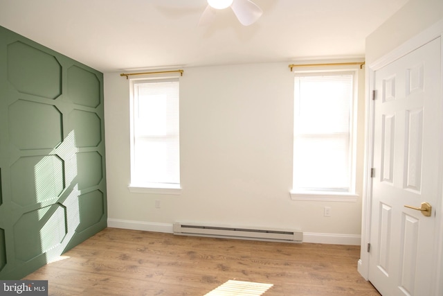 unfurnished bedroom featuring baseboards, multiple windows, baseboard heating, and light wood-style floors