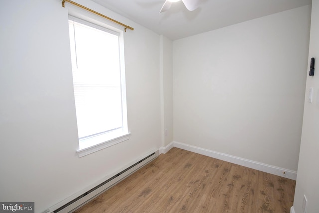 spare room with a baseboard heating unit, ceiling fan, light wood-type flooring, and baseboards