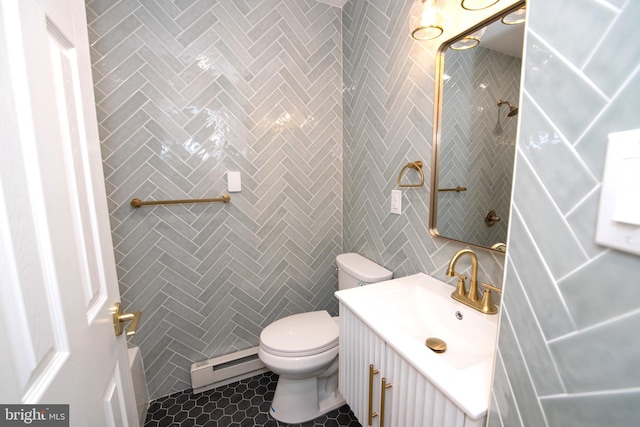 bathroom with a baseboard radiator, tile patterned flooring, toilet, vanity, and tile walls