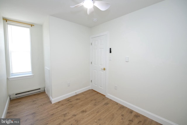 interior space with a baseboard heating unit, ceiling fan, light wood-style flooring, and baseboards