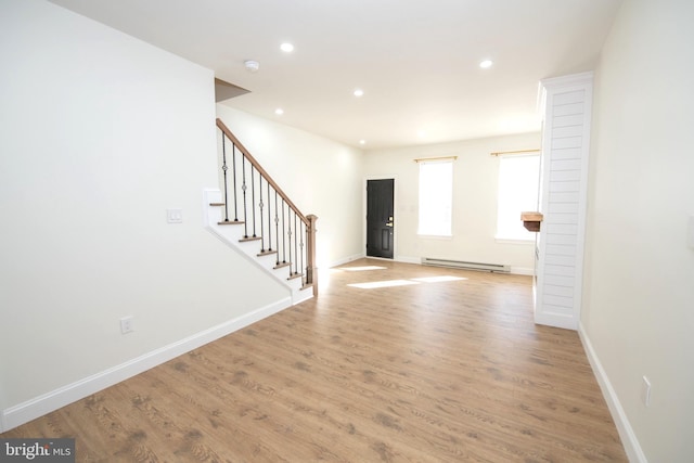 entrance foyer featuring a baseboard radiator, baseboards, light wood finished floors, and stairs