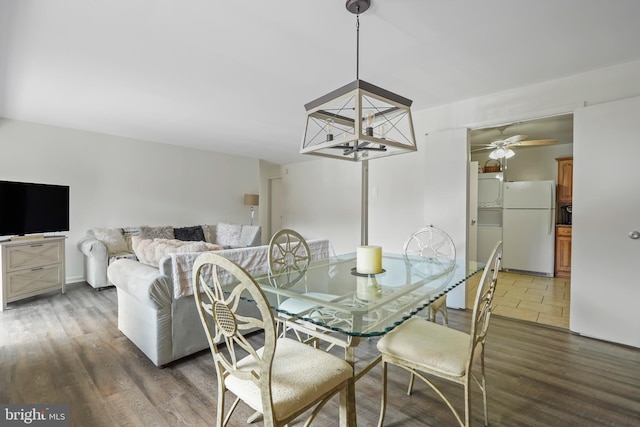 dining space featuring dark wood-style floors and ceiling fan with notable chandelier