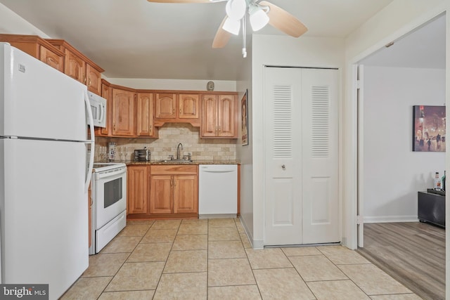 kitchen featuring tasteful backsplash, white appliances, a sink, and light tile patterned floors