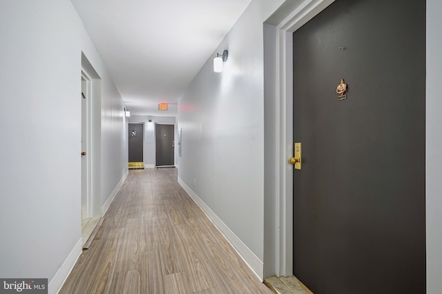 corridor with baseboards and light wood finished floors