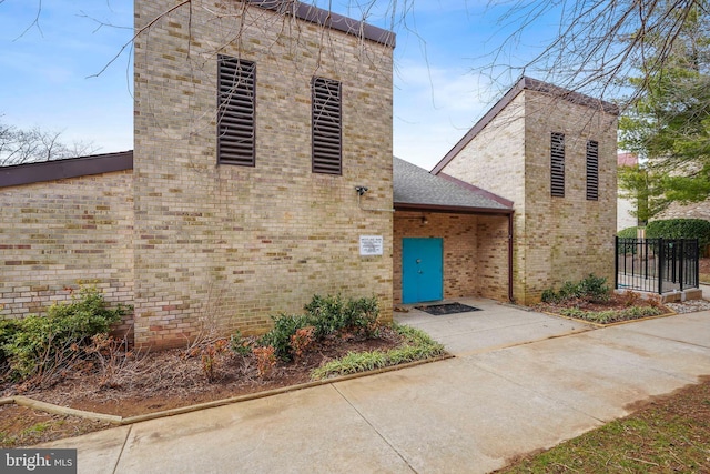 view of front of property featuring brick siding, roof with shingles, and fence