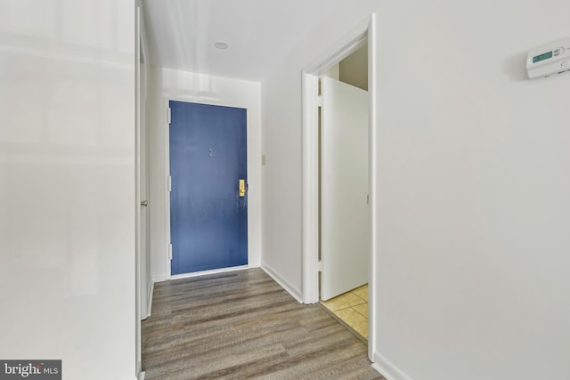 corridor with light wood-style flooring and baseboards