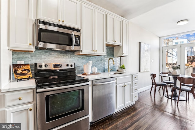 kitchen featuring tasteful backsplash, light countertops, appliances with stainless steel finishes, dark wood-type flooring, and a sink