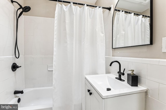 full bathroom with shower / tub combo, tile walls, and vanity