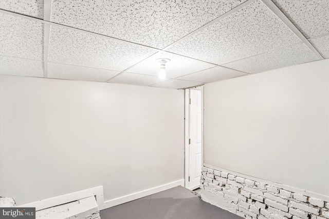 finished basement featuring a drop ceiling and baseboards