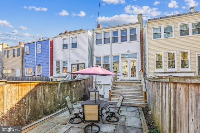 rear view of property featuring a patio, french doors, outdoor dining space, and fence