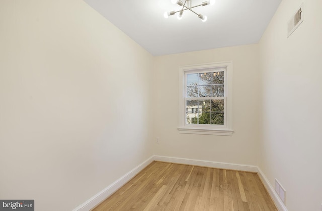 empty room with light wood-style floors, baseboards, and visible vents