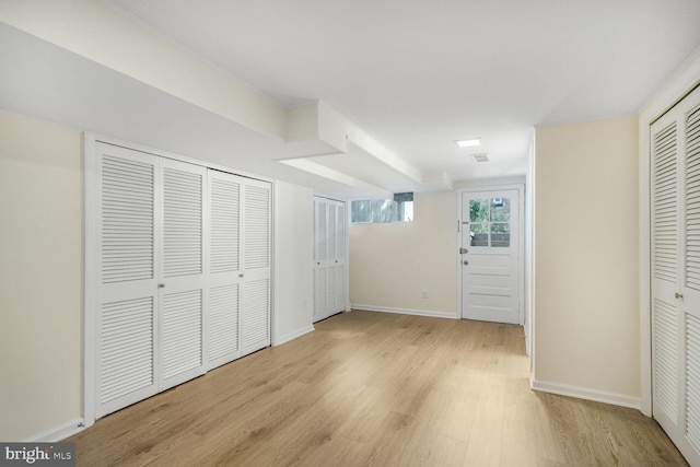 unfurnished bedroom with light wood-style floors, baseboards, and two closets