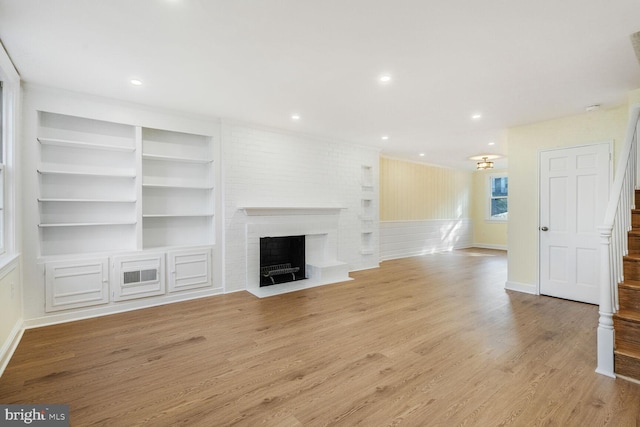 unfurnished living room with built in shelves, a fireplace, recessed lighting, wood finished floors, and baseboards