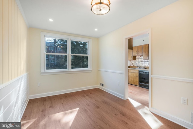 unfurnished room with light wood-style floors, baseboards, a sink, and recessed lighting