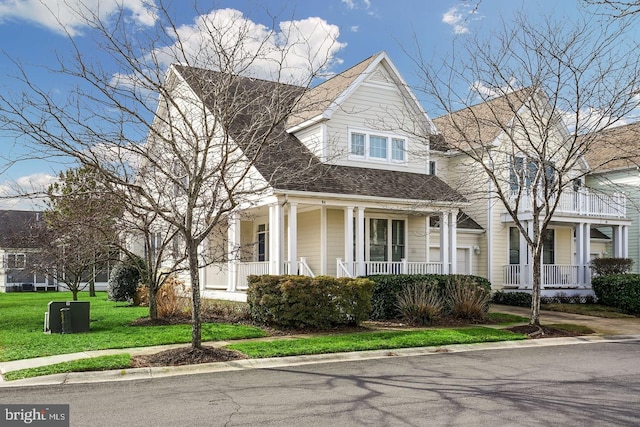 view of front of house with a front yard, covered porch, and roof with shingles